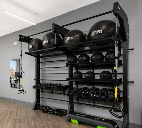 A gym with wooden floors and a variety of exercise equipment.