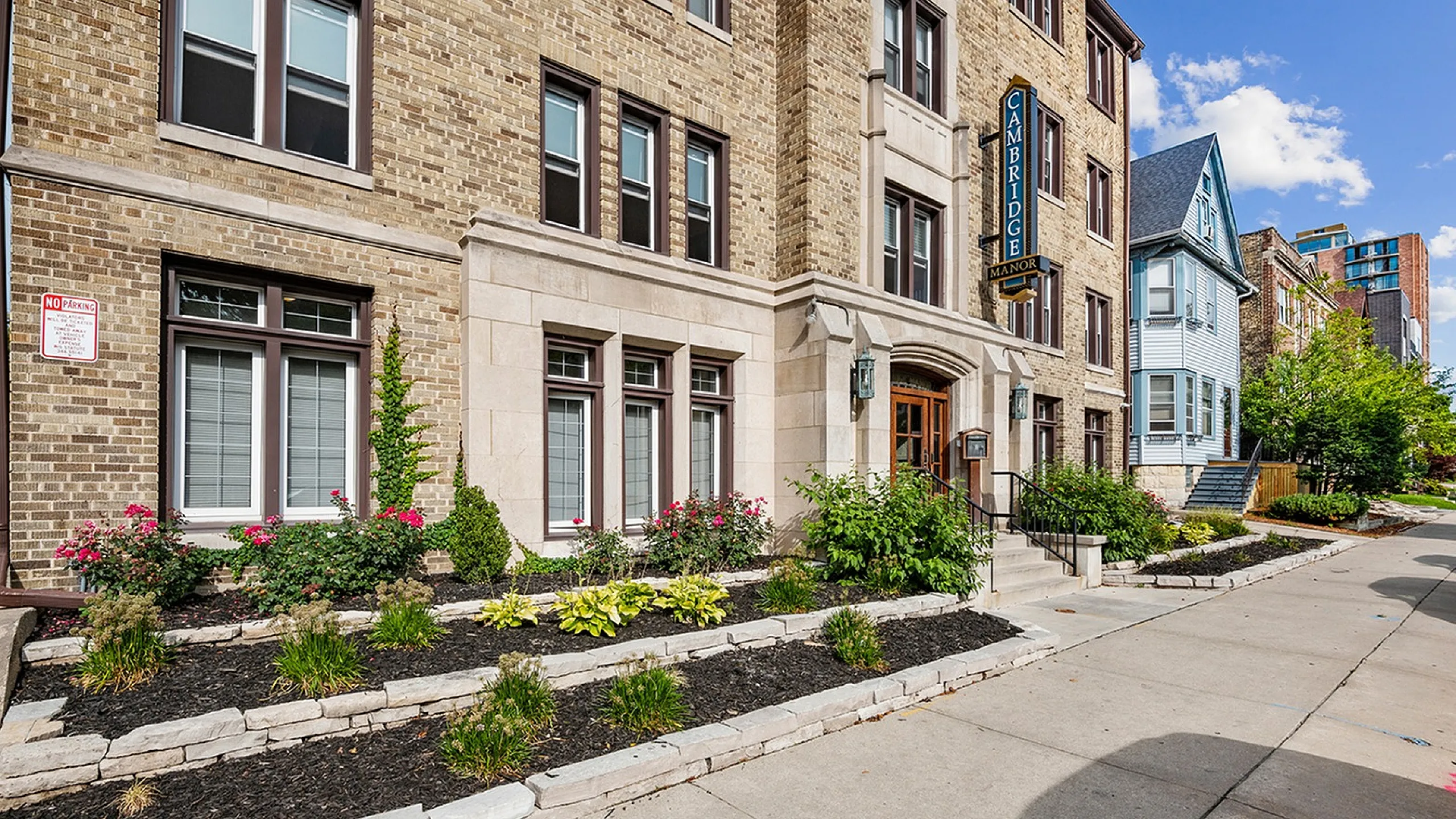 Charming brick apartment building with elegant landscaping and inviting entrance, offering urban living in a picturesque setting.