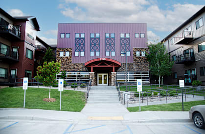 A building with a red door and a stone wall in front.