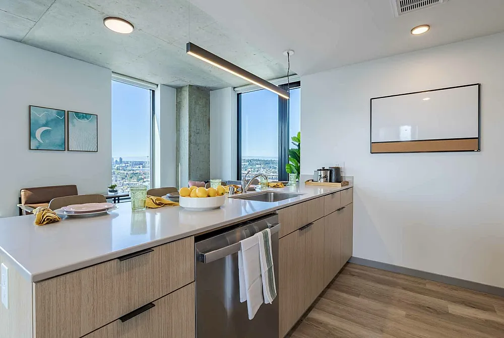 Model apartment kitchen with light cabinets, granite countertops, and stainless steel appliances