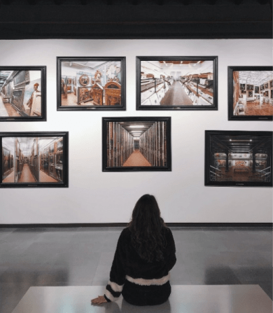 Woman sitting in front of a wall of photos. Elle's apartments are nearby museums & latest exhibits in Washington, DC.