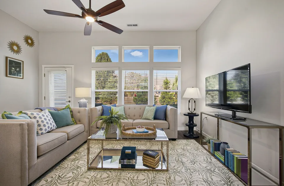 Bright and inviting living room showcasing modern decor, plush sofas, a large TV, and ample natural light through expansive windows.