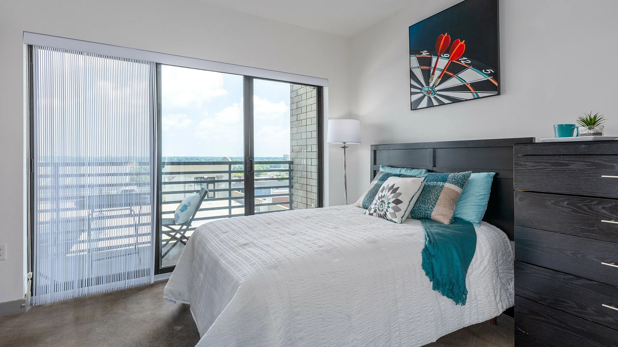 Modern bedroom with a comfortable bed, stylish decor, and a sliding glass door leading to a balcony with scenic views.