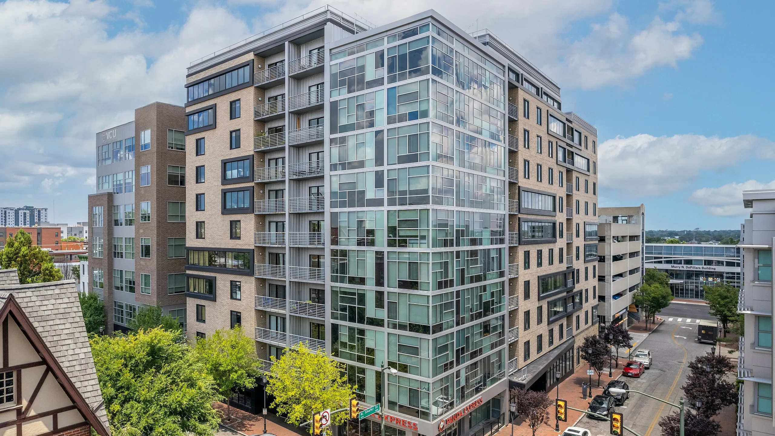 Contemporary multi-story apartment building with glass and brick facade in a vibrant urban setting.