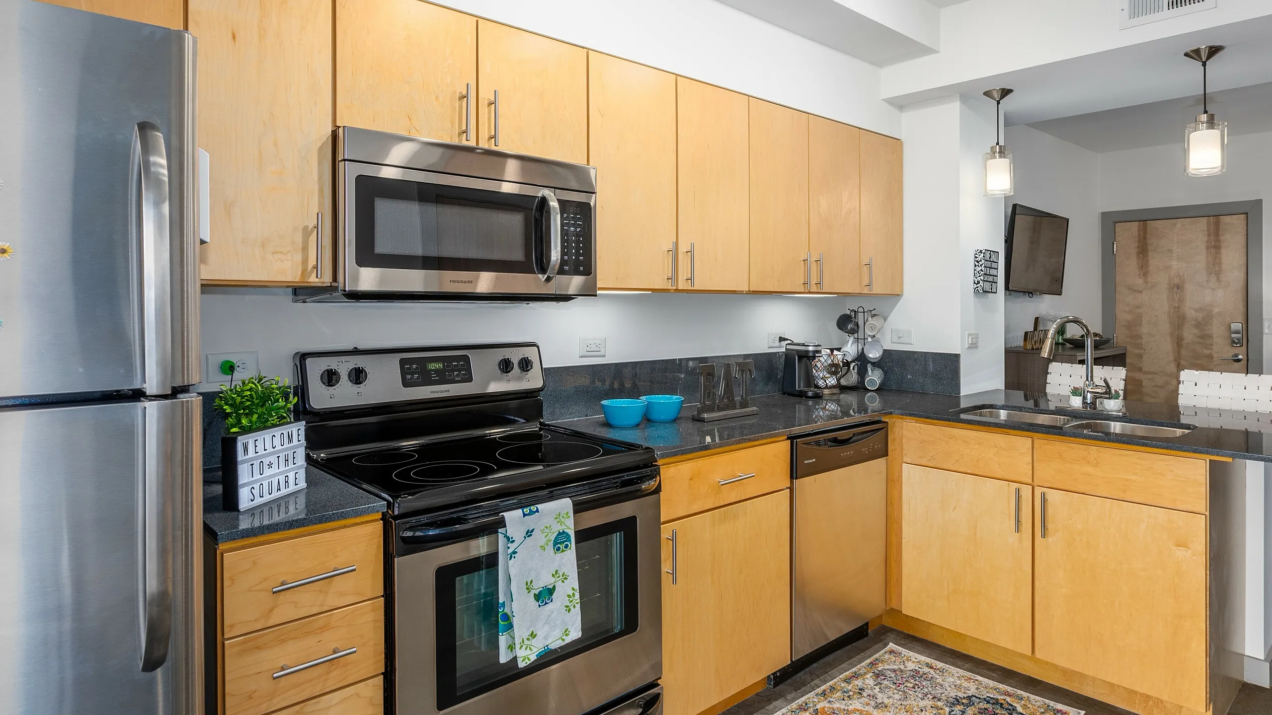 Modern kitchen with stainless steel appliances, light wood cabinets, and a stylish open layout.
