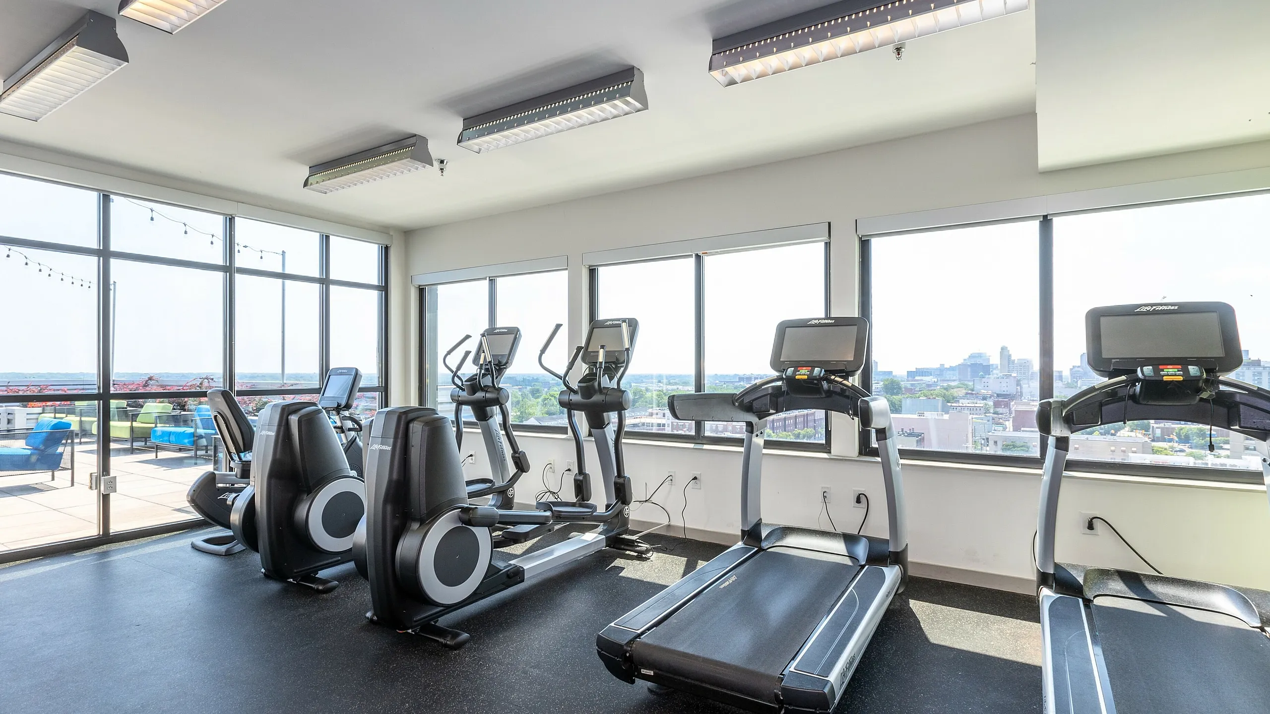 Bright and modern fitness center with treadmills and ellipticals, overlooking a scenic city view.