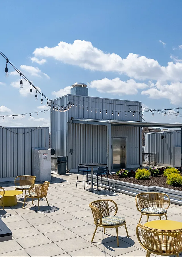 Stylish rooftop patio with string lights, seating area, and cityscape views.