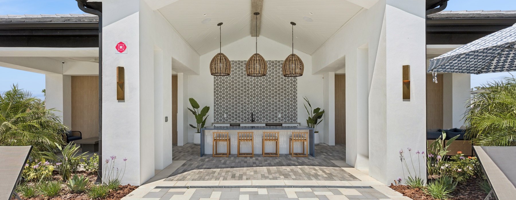 an outdoor community kitchen area with an island and chairs