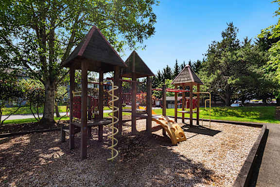 a playground with a swing set and other play equipment at Eagles Landing Apartments, Everett, WA