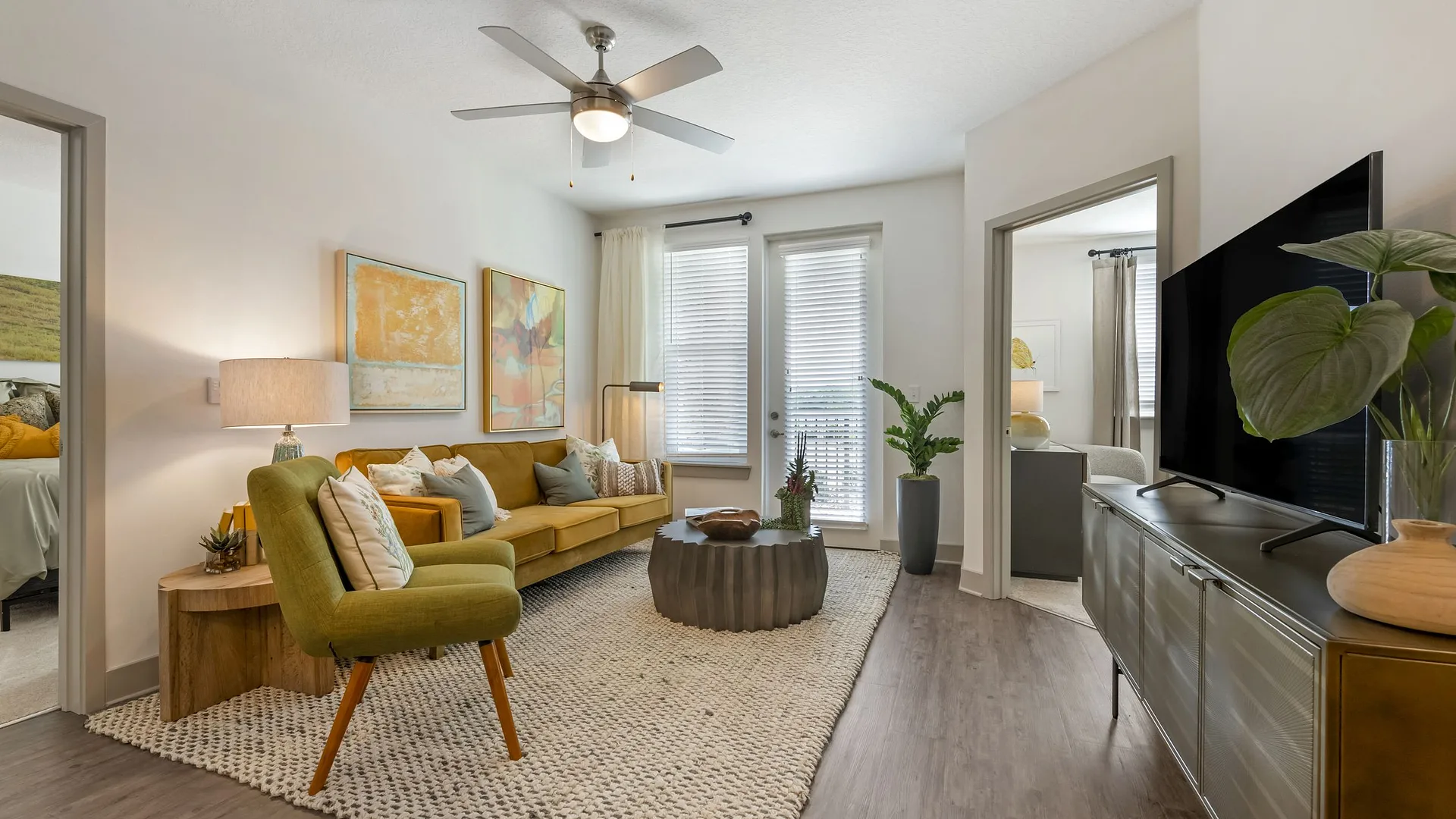 A cozy living room with modern furniture, a fan, and bright decor.