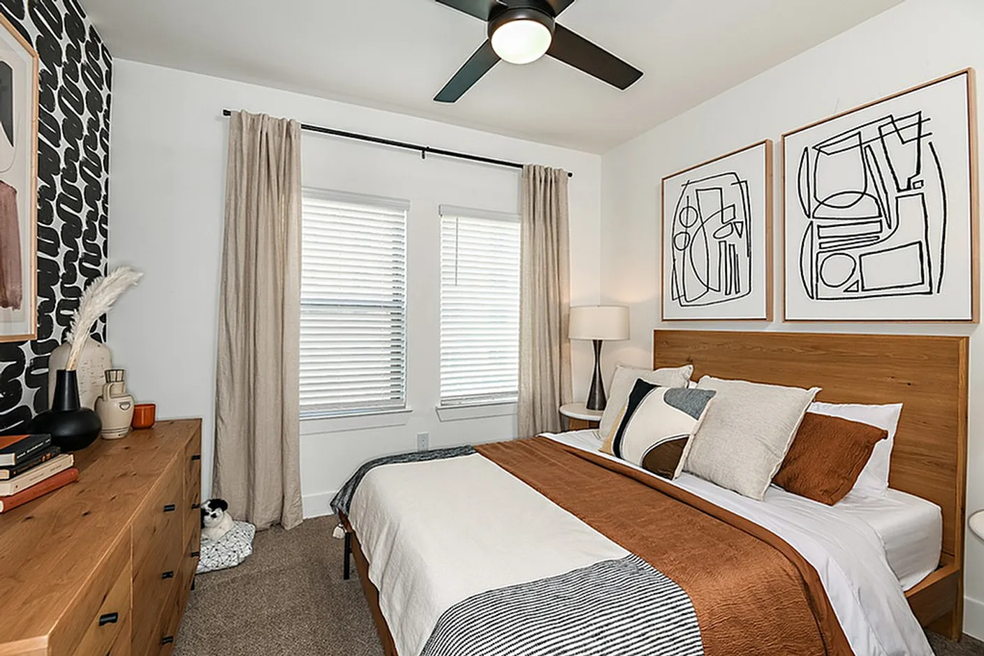 Elegant bedroom with modern decor, featuring cozy brown and white bedding, abstract wall art, and chic wooden furniture.