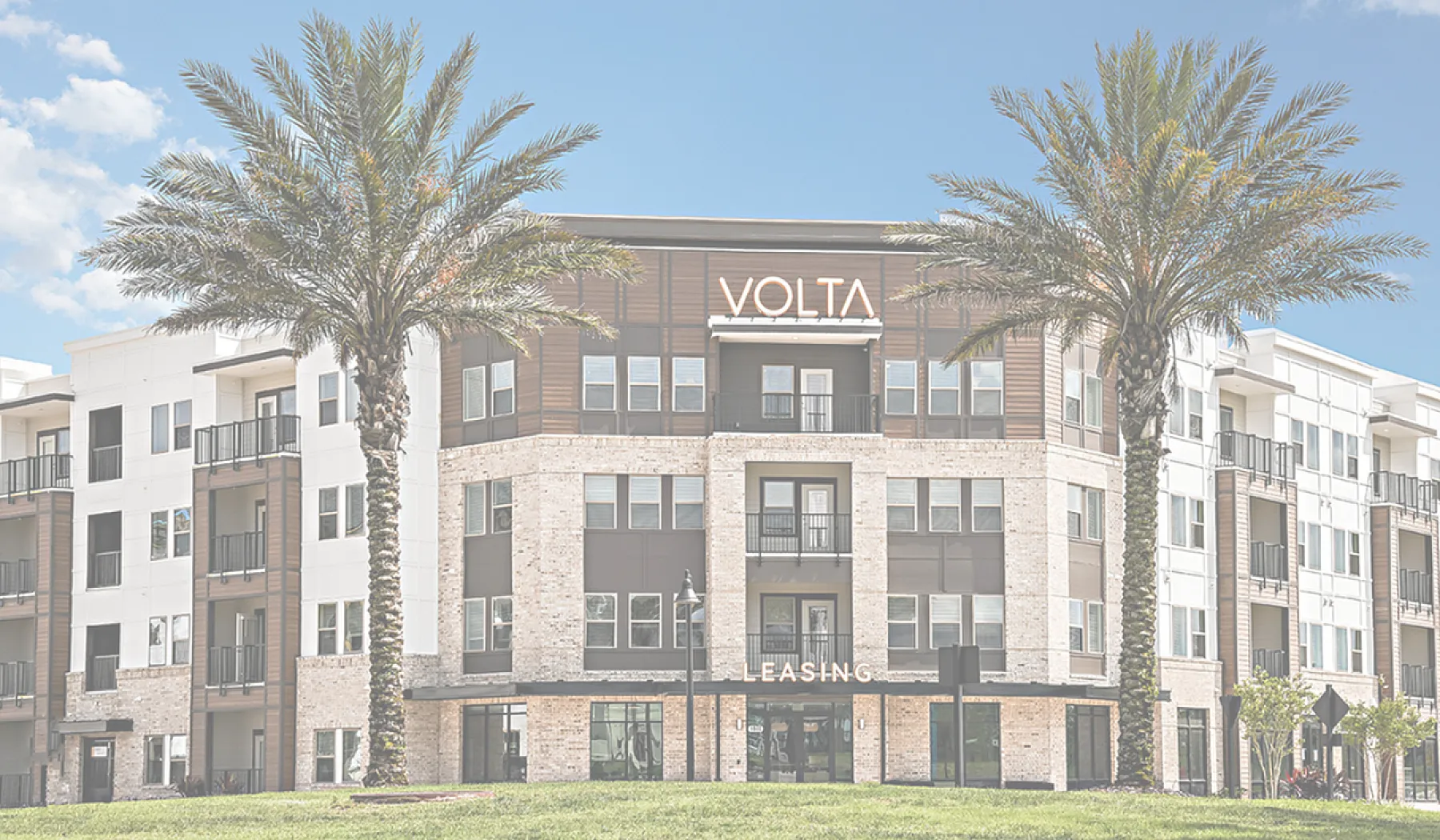 Elegant apartment community with modern design, featuring manicured lawns and palm trees under a clear blue sky.
