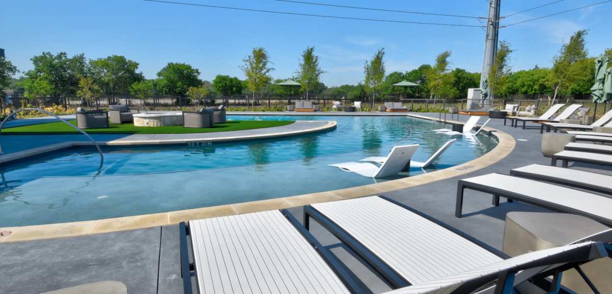 A swimming pool area with lounge chairs at The Palo in Fort Worth, Texas