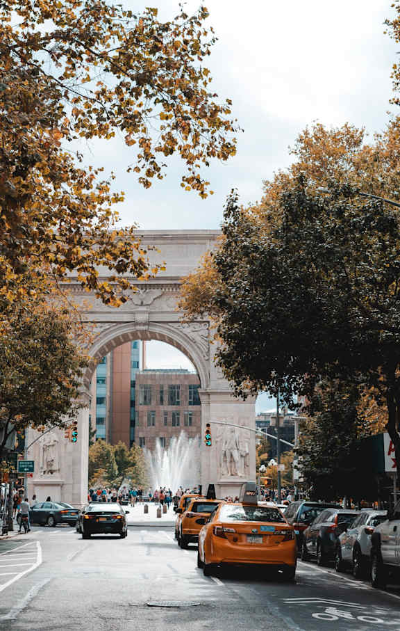 A cityscape with a dense urban area and a park with autumn trees.