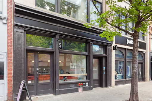 A storefront with a black awning and a tree in front.