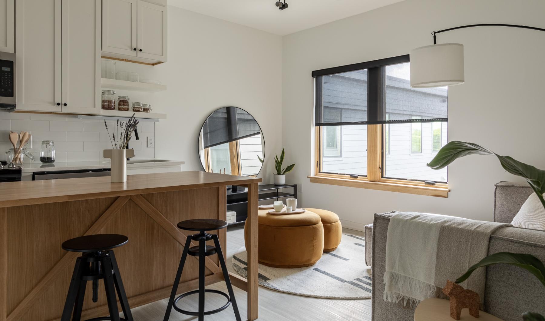 a kitchen island with a bar stool and a table connected to a living room