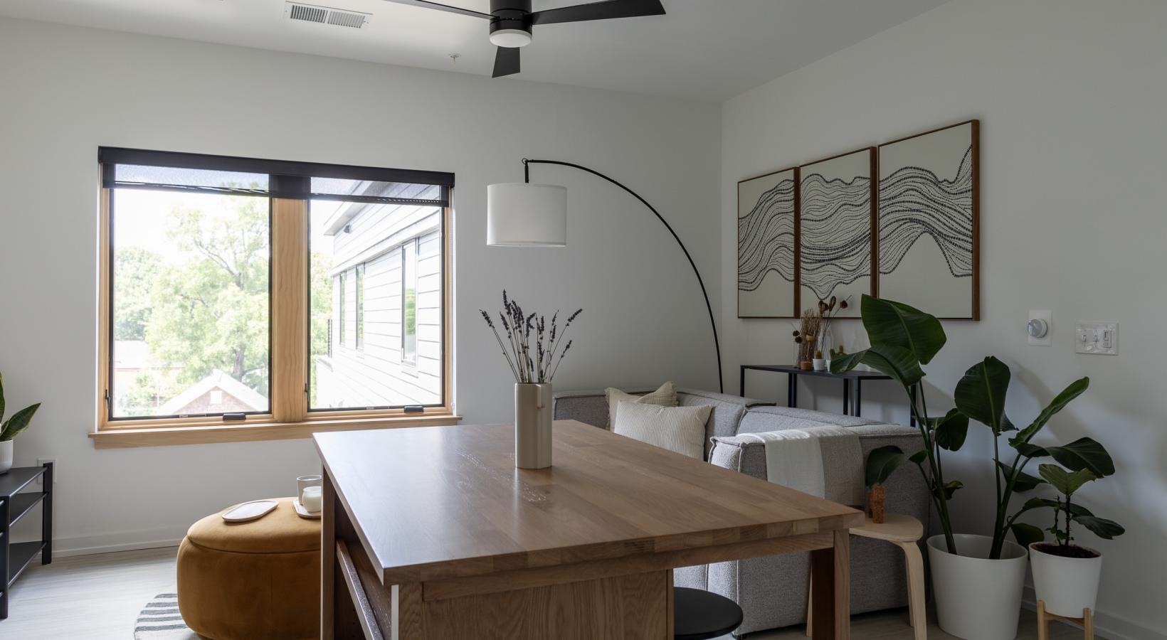 a wood island in front of a living room with windows