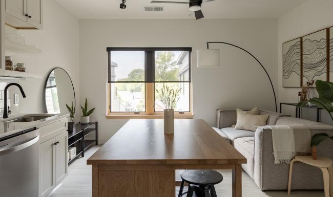 a kitchen island with chairs and a living room beyond