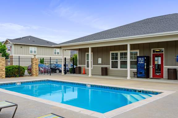 A pool in front of a house with a red door.