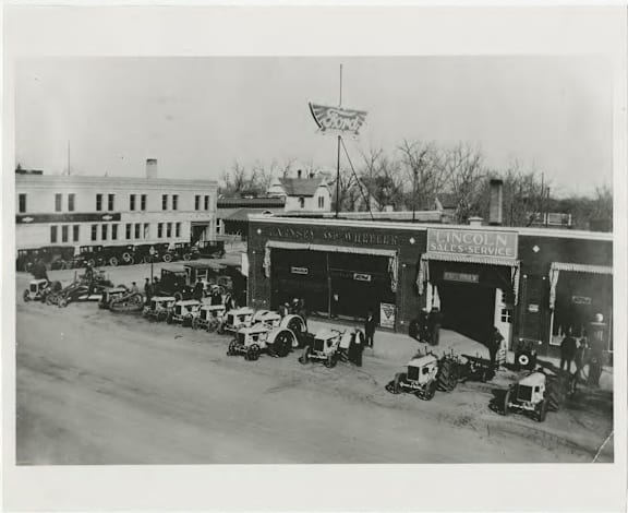 A black and white photo of a Lincoln dealership with several cars parked in front.