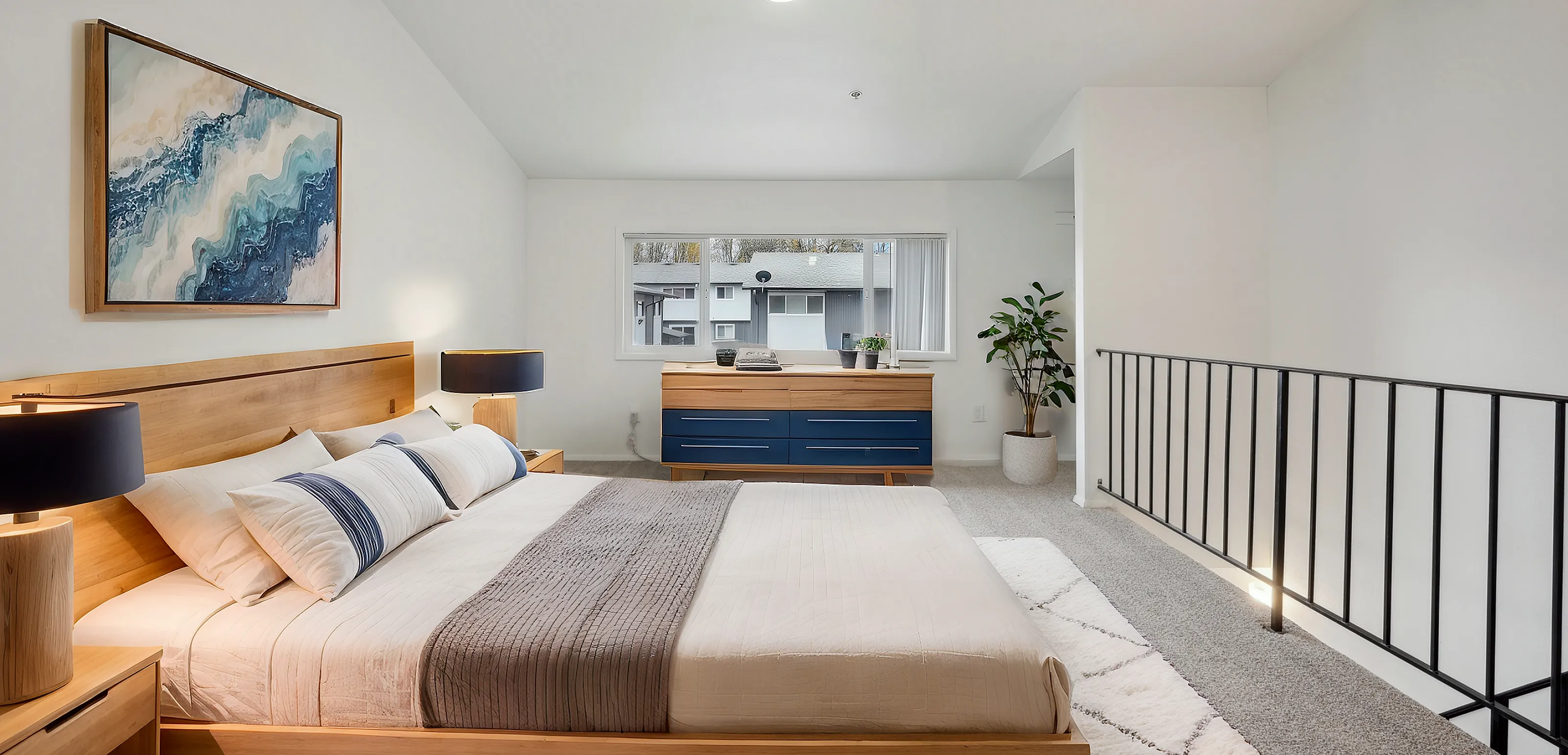 Spacious modern bedroom with a large bed, cozy bedside lamps, artwork, and a window view.