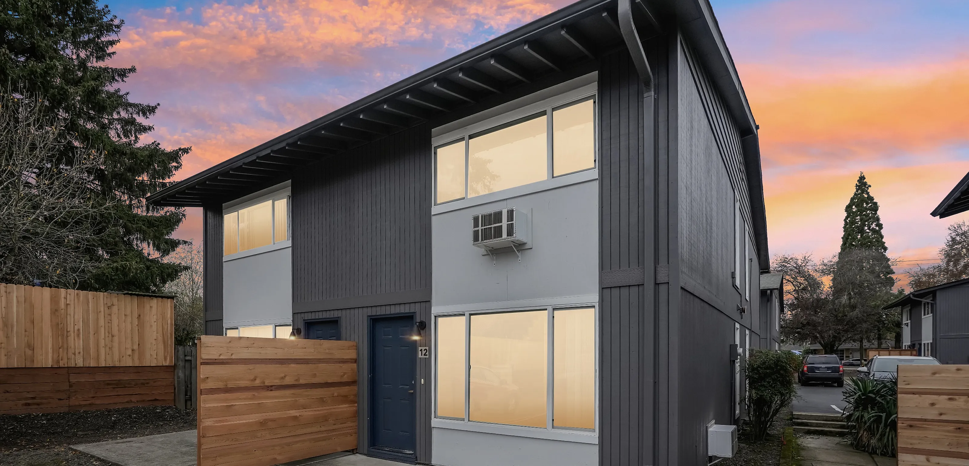 Modern duplex building with a sleek design and large windows at sunset.
