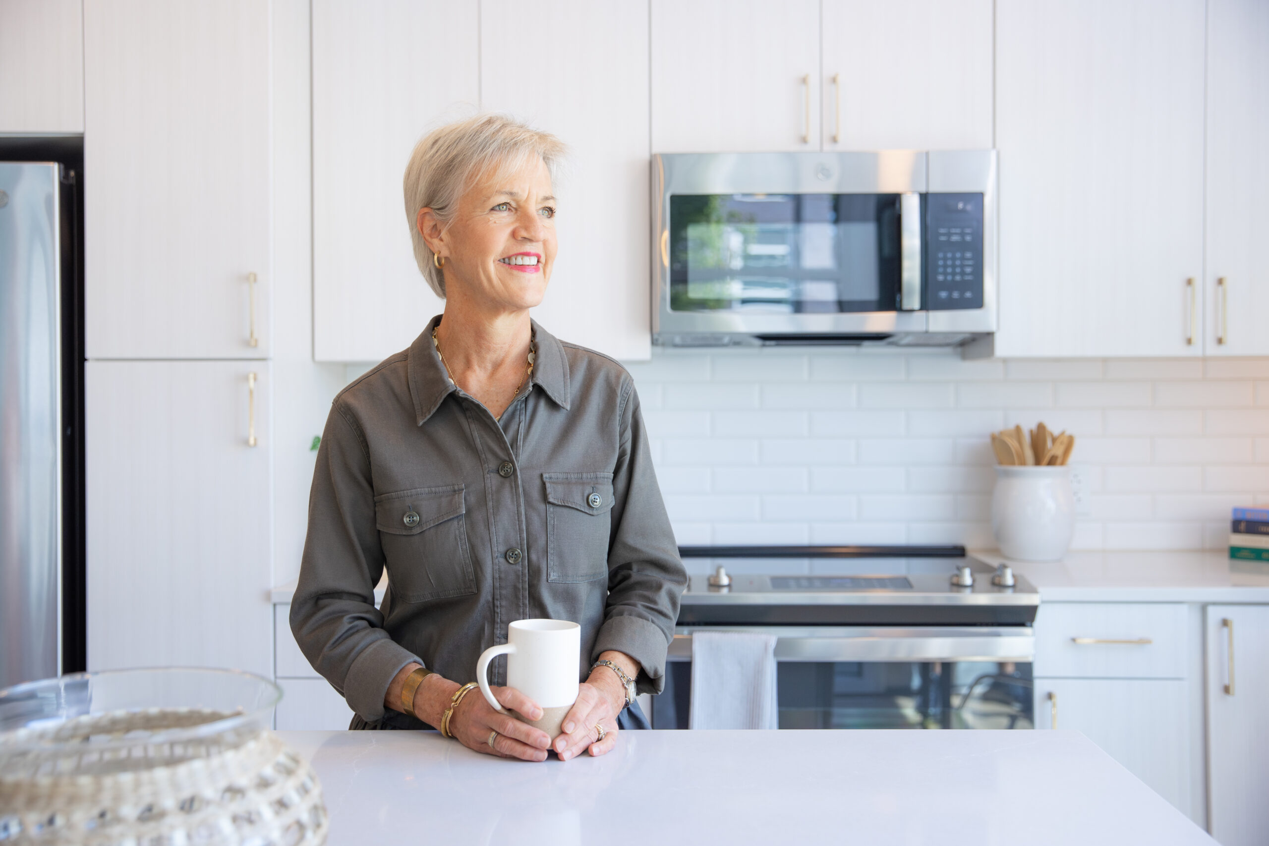 Close-up image of a woman smiling and holding a cup in a Highland North Hills apartment kitchen