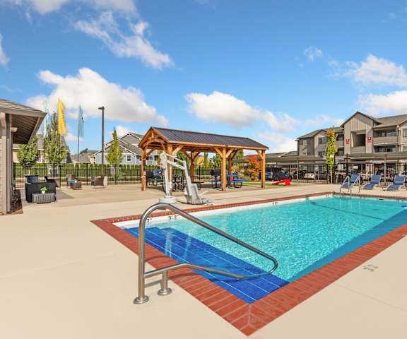 A large swimming pool with a diving board and a building in the background.