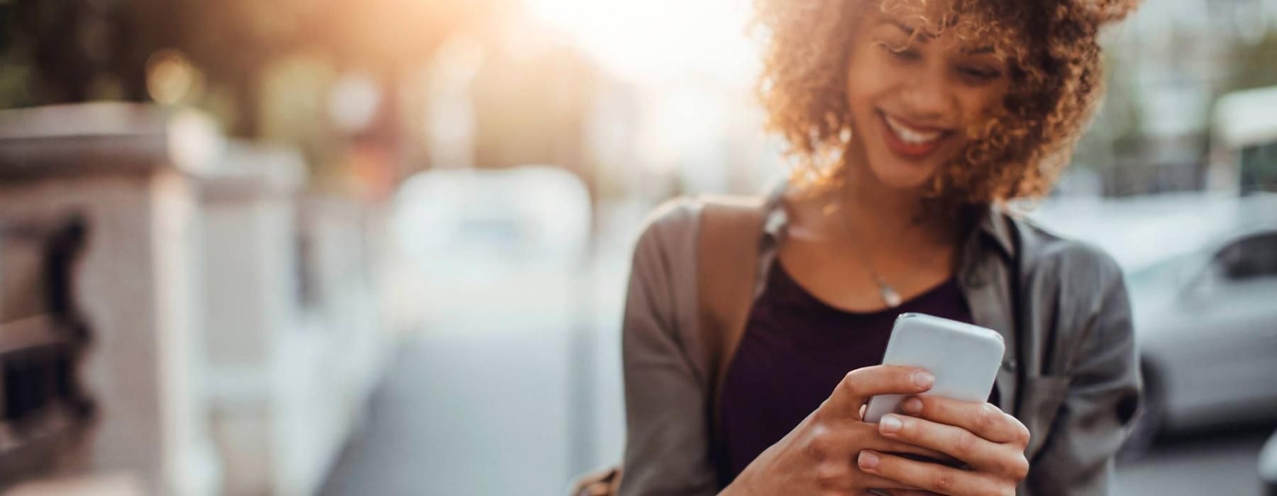 Woman walking down the street holding her phone