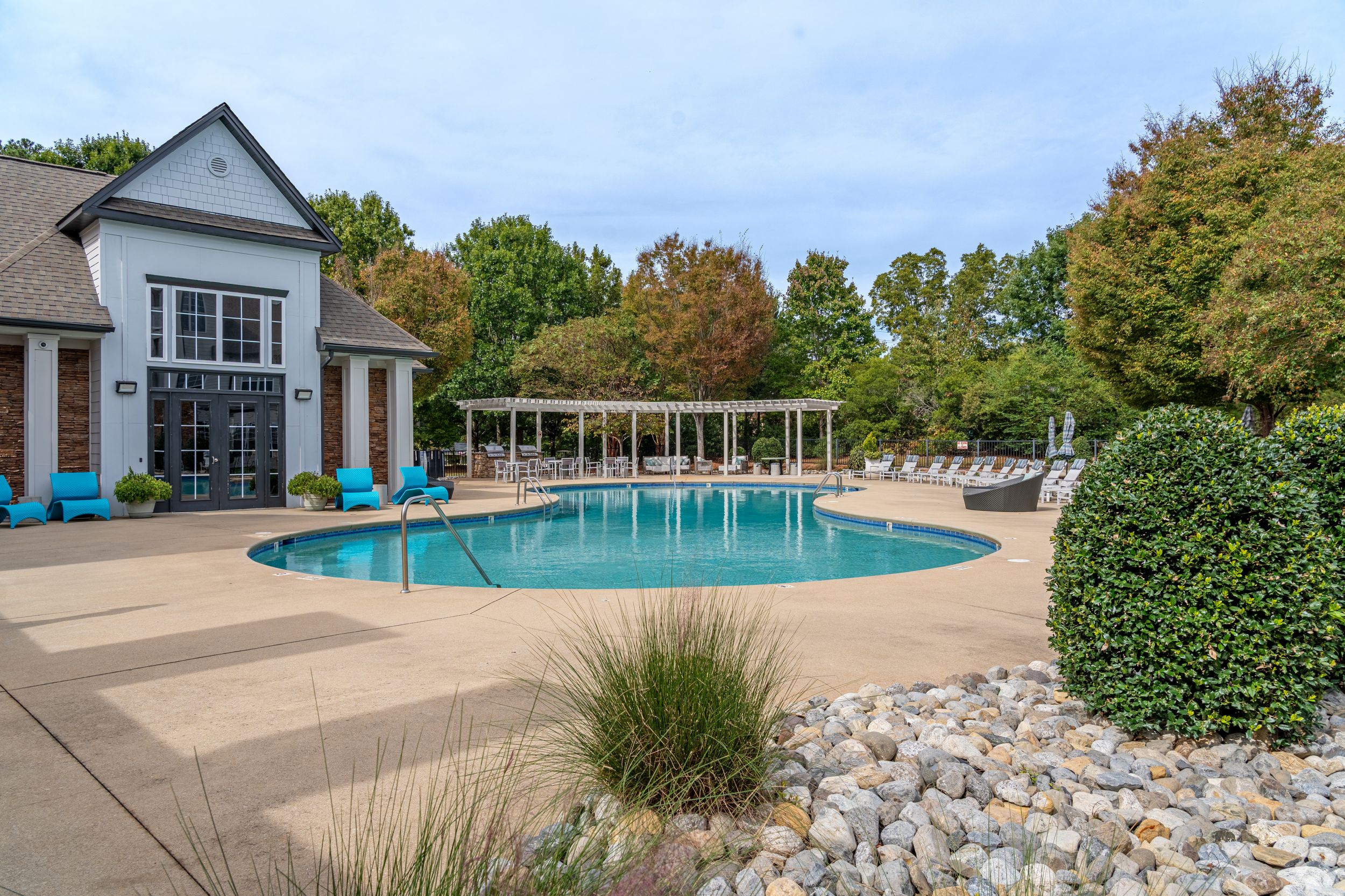 A serene pool area with lounge chairs and greenery around it, perfect for relaxation.