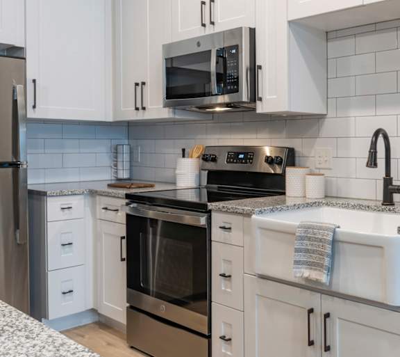 A modern kitchen with white cabinets and stainless steel appliances.