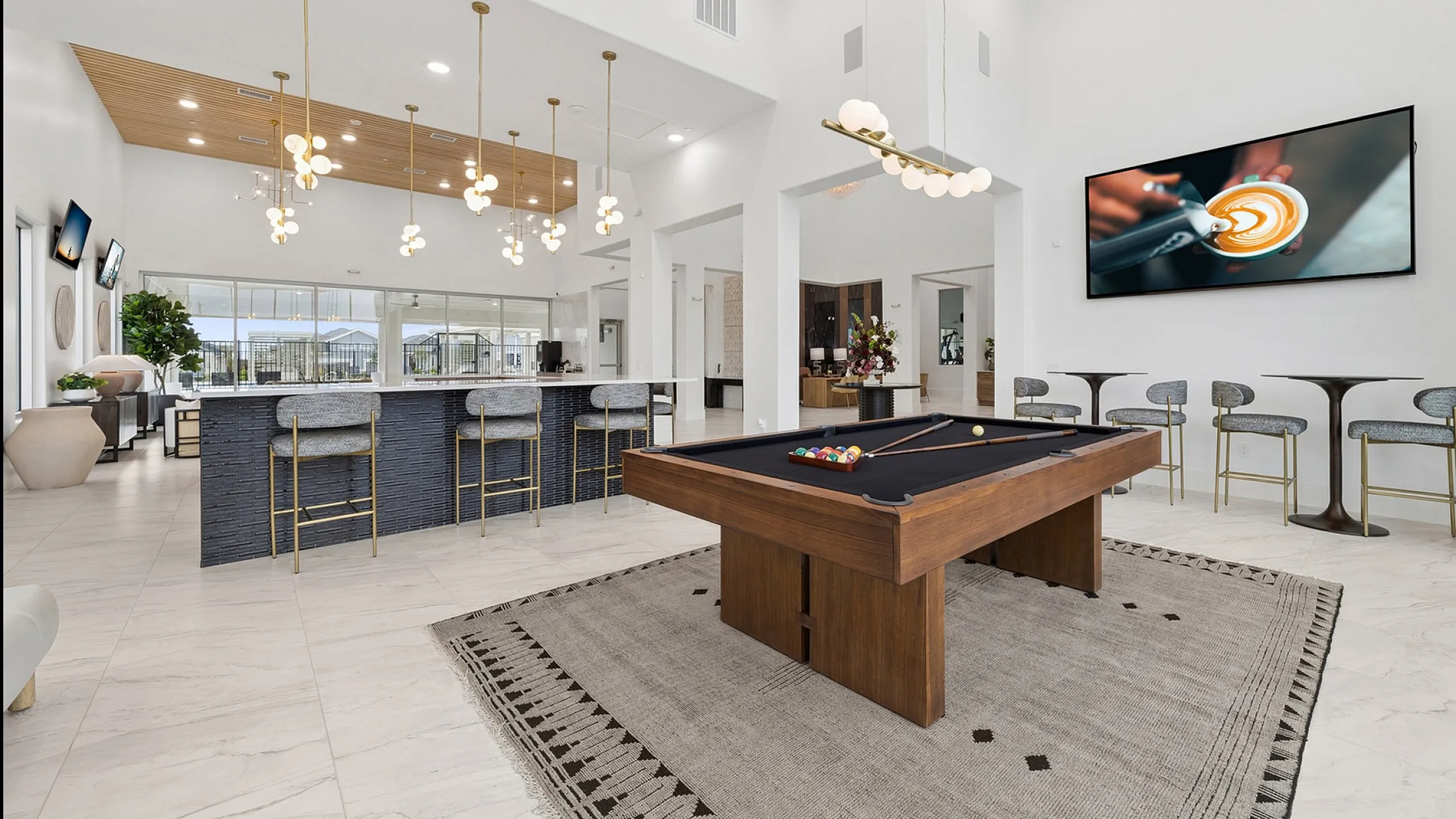 Luxurious open-concept living space featuring a chic bar area with elegant lighting, plush seating, and a stylish pool table for entertainment.