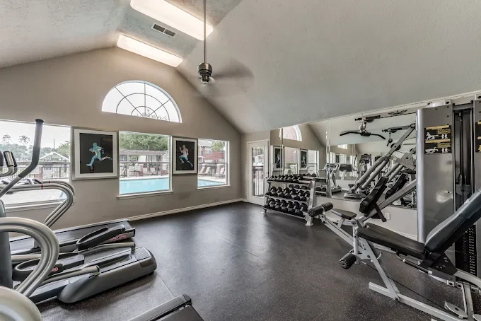 Fitness Center with treadmill, weight training equipment, and large windows with a view of a swimming pool.