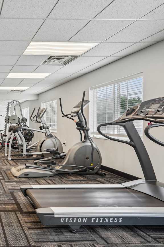A gym with a variety of equipment including treadmills, weights, and exercise machines.