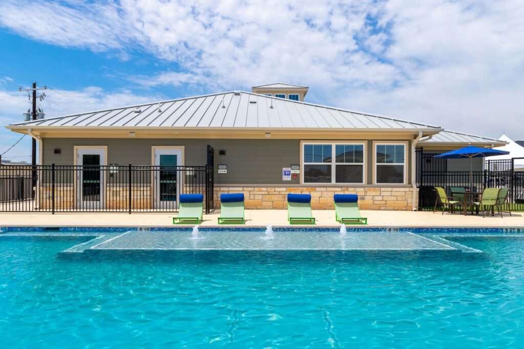 Swimming pool with poolside seating and clubhouse at Menchaca Commons