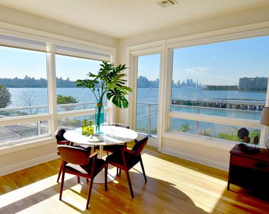 A dining room with a table and chairs and a view of the water.