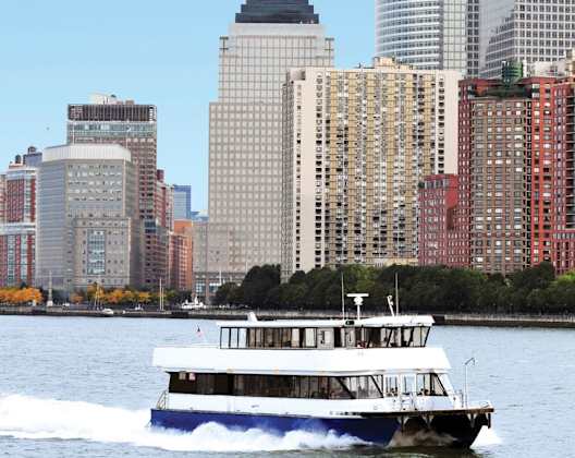 A boat is sailing on the water in front of a city skyline.