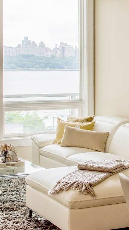 A living room with a white couch and a painting on the wall.