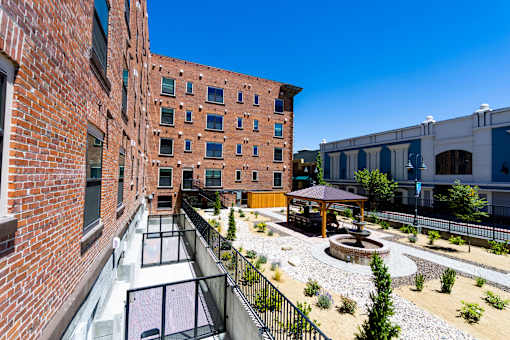 A courtyard with a fountain and a gazebo is surrounded by brick buildings.