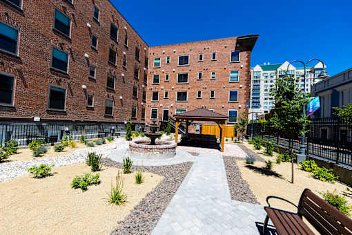 A courtyard with a fire pit and benches is surrounded by brick buildings.