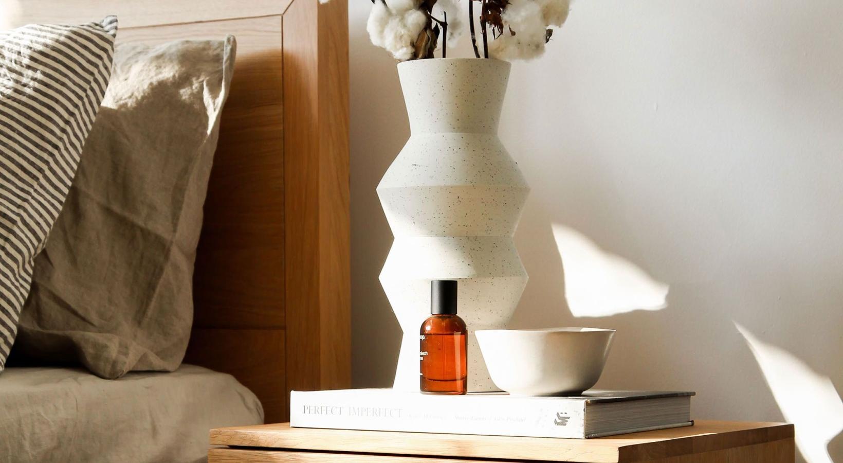 a vase with cotton stems on a bedside table