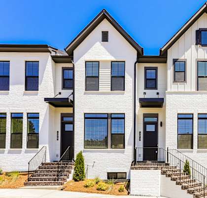 A white two-story house with black railings and a black door.