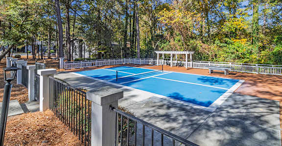 A blue pool surrounded by a fence and trees.