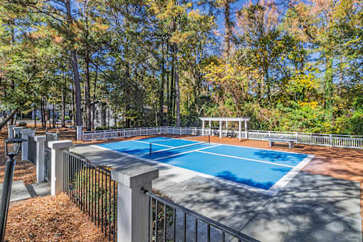 A blue pool surrounded by a fence and trees.