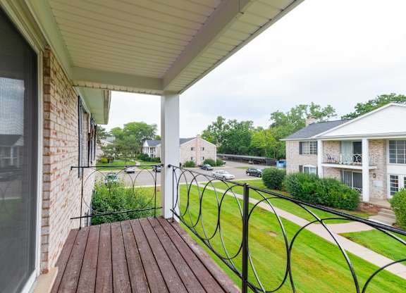 A balcony with a black railing and a brown wooden floor.