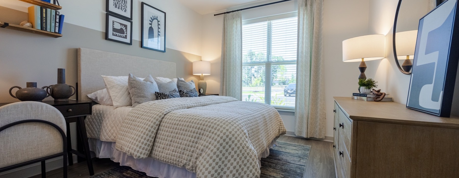 Madison Ironbridge bedroom with upholstered bed, neutral décor, dresser, and large window with natural light.