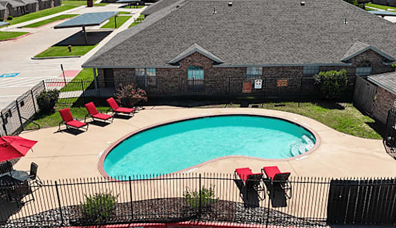 A black fence surrounds a pool and patio area.