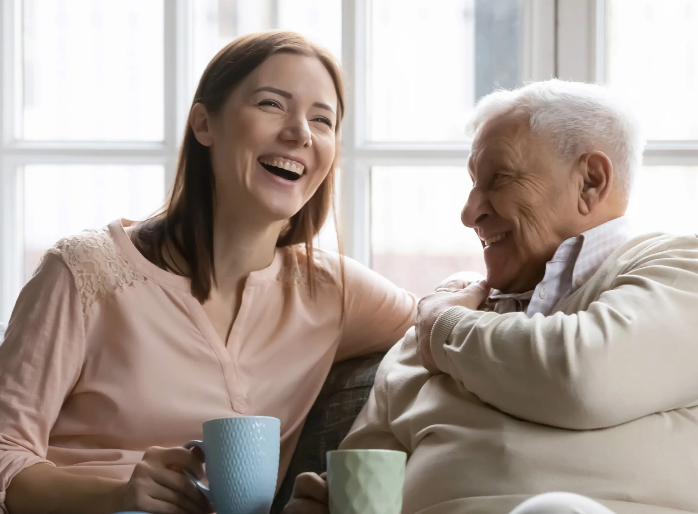 smiling young woman sitting with senior man drinking coffee