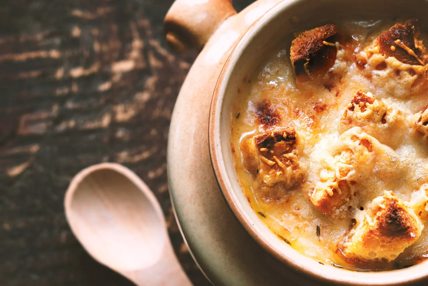 Freshly made French onion soup topped with melted cheese and toasted bread, served in a white bowl