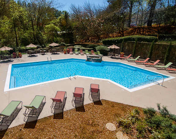 A large swimming pool surrounded by red chairs and umbrellas.